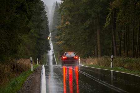 car braking on wet road showing brake lights